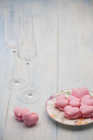 pink cookies in the shape of hearts on a plate and champagne glasses on wooden boards on Valentine's Dayの写真素材