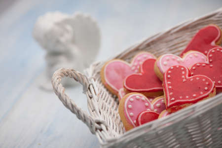 pink cookies in the form of hearts in a square wicker basket close-upの写真素材