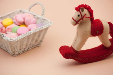 pink cookies in the shape of hearts and colorful round cookies in a wicker basket and toy horse on Valentine's Dayの写真素材