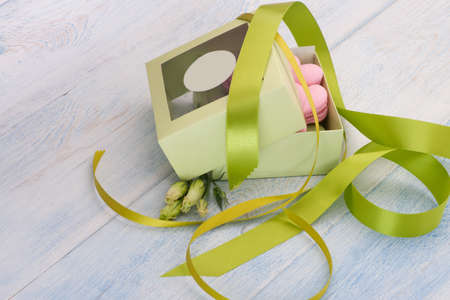 pink cookies in the shape of a heart in a gift box adorned with ribbon and flowers on wooden boards on Valentine's Dayの写真素材
