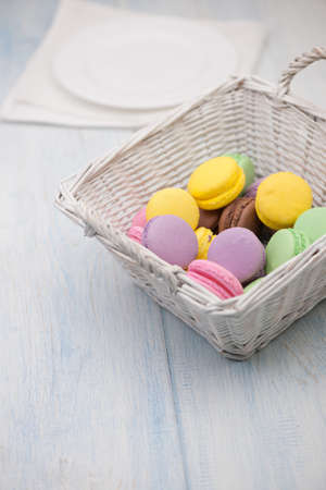 multi-colored circular cookies in a wicker basket and a plate on a napkinの写真素材