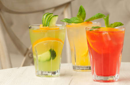 three glass of transparent glass with juice and lemon on the table against the background of the chair and sofaの写真素材