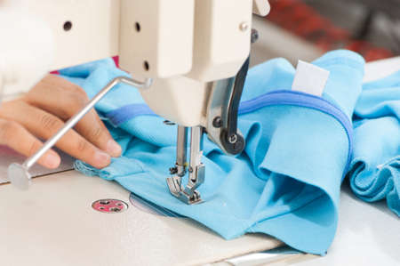 closeup seamstress on the machine sews clothes at a garment factoryの写真素材