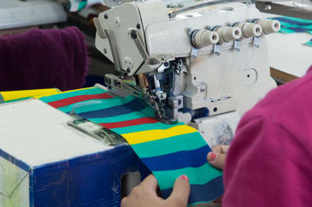 closeup seamstress on the machine sews clothes at a garment factoryの写真素材