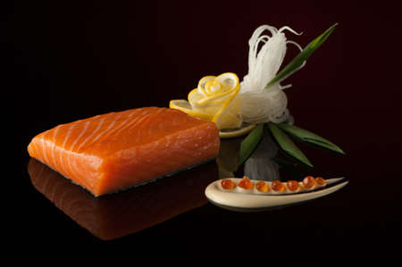 piece of sushi with lemon and leaf on a dark background with reflectionの写真素材