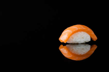 closeup of sushi with rice on black background with reflectionの写真素材