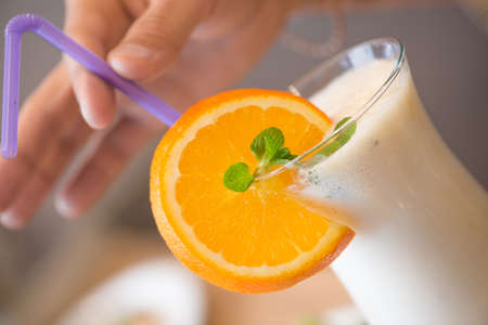 in the hands of a milkshake with a slice of lemon and a strawの写真素材