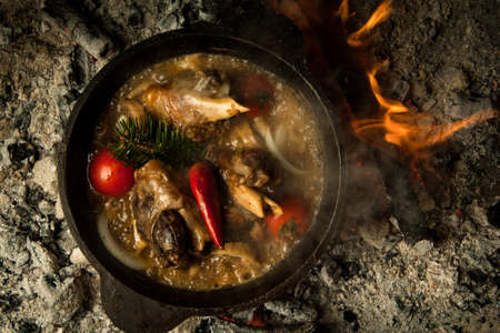 meat soup with vegetables prepared on burning coals. the dish is cooked and smoked on charcoalの写真素材
