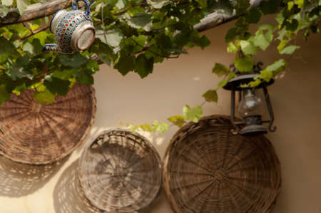kettle and kerosene lamp hanging on a tree branch against the background of wicker traysの写真素材