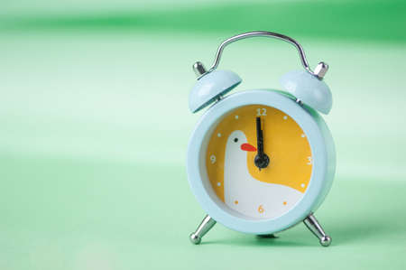 blue clock with a bird pattern on a green blurred backgroundの写真素材