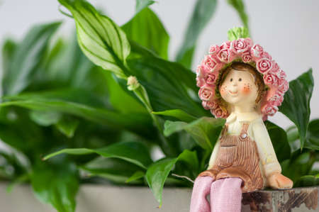 a souvenir statuette of a girl sitting on a background of foliageの写真素材