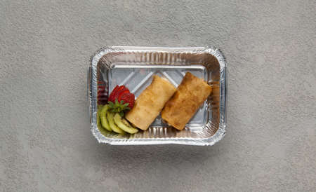 fast food in a foil box on a gray background. a healthy food close up