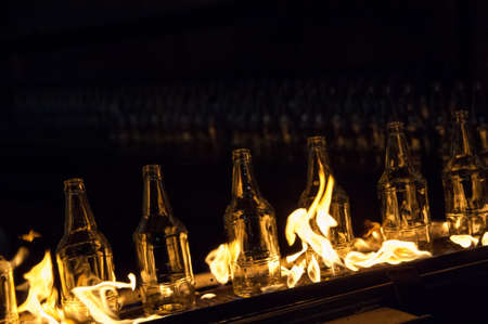 plant for the production of glass bottles. glass bottles on a conveyor belt with fireの写真素材