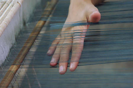 weaving and manufacturing of handmade fabric close up. women's hands behind a loom make clothの写真素材