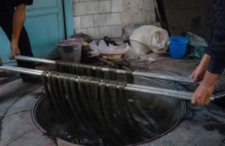 dyeing of finished yarn. two men manually dye yarnの写真素材