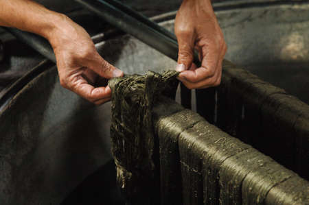 painting threads and yarns. male hands paint the cloth in the trough