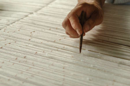 hand with a pencil makes marks on the carpet. weaving and manufacturing of handmade carpets closeup