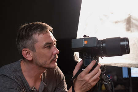 a young photographer with a camera on the background lighting equipmentの写真素材