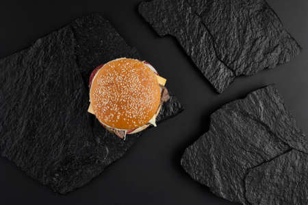 juicy cheeseburger on a background of black stone plates. the view from the topの写真素材