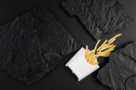 french fries in white box on a background of black stone plates. the view from the topの写真素材