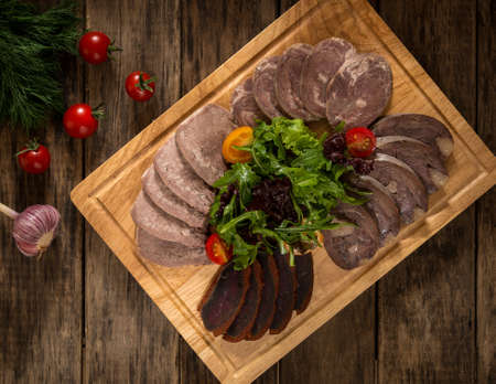 sliced meatloaf on a wooden tray and is decorated with vegetables, top viewの写真素材