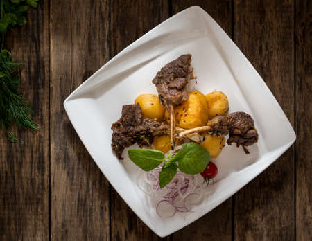 a dish of meat and potatoes in a plate on wooden background, top viewの写真素材