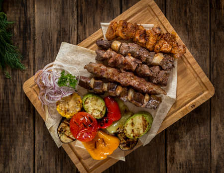 juicy pieces of grilled meat with vegetables on the kitchen board, top viewの写真素材