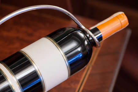 a bottle of wine in a metal stand on the background of the tableの写真素材