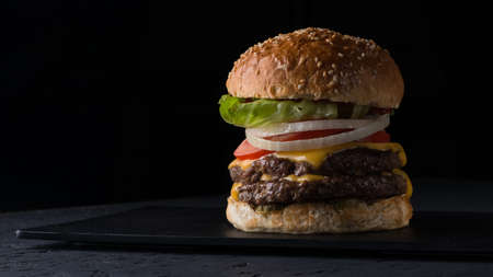 juicy cheeseburger on a flat plate on a black background, close-upの写真素材