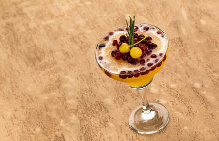 Yellow fruit cocktail with berries on light brown backgroundの写真素材