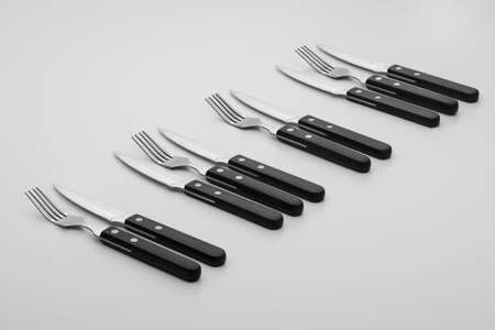 forks and knives in a row on a light backgroundの写真素材