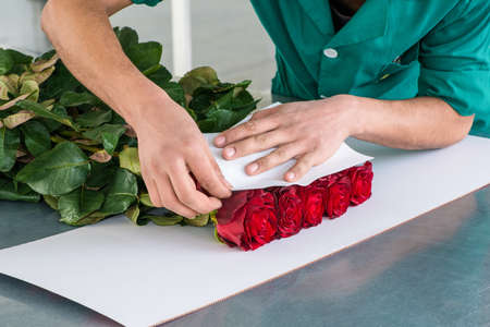 the man packages the flowers with a paper, preparation for transportの写真素材