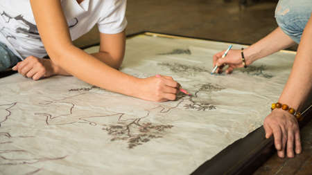 two girls painters draw a sketch through tracing paper, close-upの写真素材