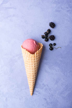 ice cream with berries in a waffle horn on an ornamental purple background, top viewの写真素材