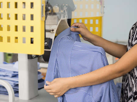 a woman in the sewing shop on the press machine gives the shape of a shirt collarの写真素材