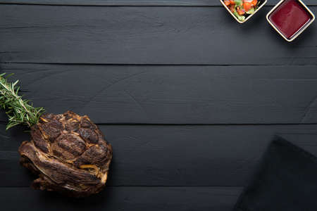 fried meat with greens, sauce and gravy on a black wooden background