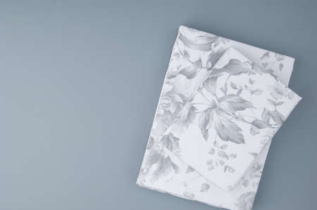 folded new bed linen with patterns on grey background, top view