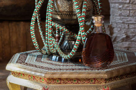 a bottle of cognac and a hookah on a richly decorated antique decorative tableの写真素材