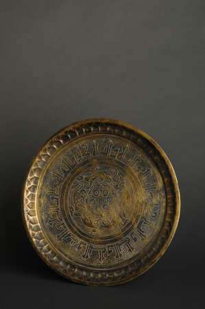 ancient oriental metal tray on dark background. antique bronze tablewareの写真素材