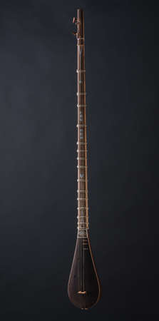 ancient Asian stringed musical instrument on black background with backlight