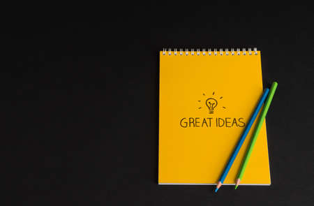 yellow notepad with colored pencils on black background, isolated. back to school. great ideas