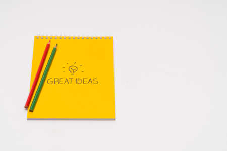 yellow notepad with colored pencils on white background, isolated. back to school. great ideas