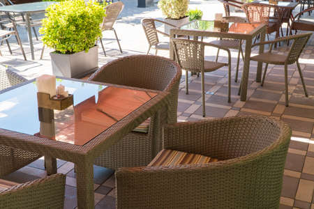 outdoor summer cafe with glass table and flower bedsの写真素材