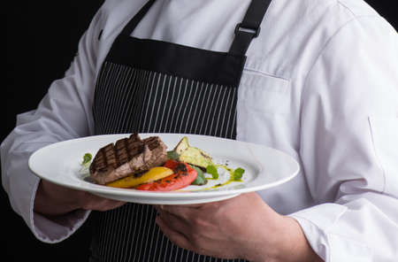 chef in uniform serves a dish in a plate