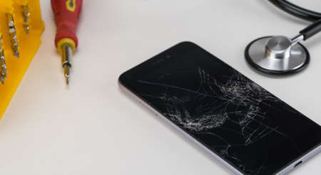 Diagnosing the phone with a stethoscope, near a screwdriver. Phone repair concept