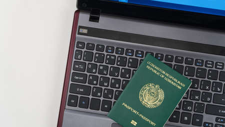 Passport of Uzbekistan on the laptop keyboard. Online registration. Top viewの写真素材