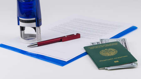 Uzbekistan passport with US dollars on the background of documents and contract. Concept - briber and corruptionの写真素材