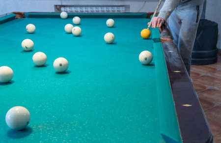 Green billiard table with white balls. Young man playing billiardsの写真素材