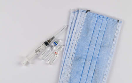 Medical protective masks on a white background with vaccine capsules and a syringe. Coronavirus...