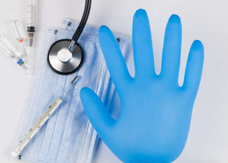 Medical mask and gloves on a white background with a stethoscope and syringe. Coronavirus Protection...
